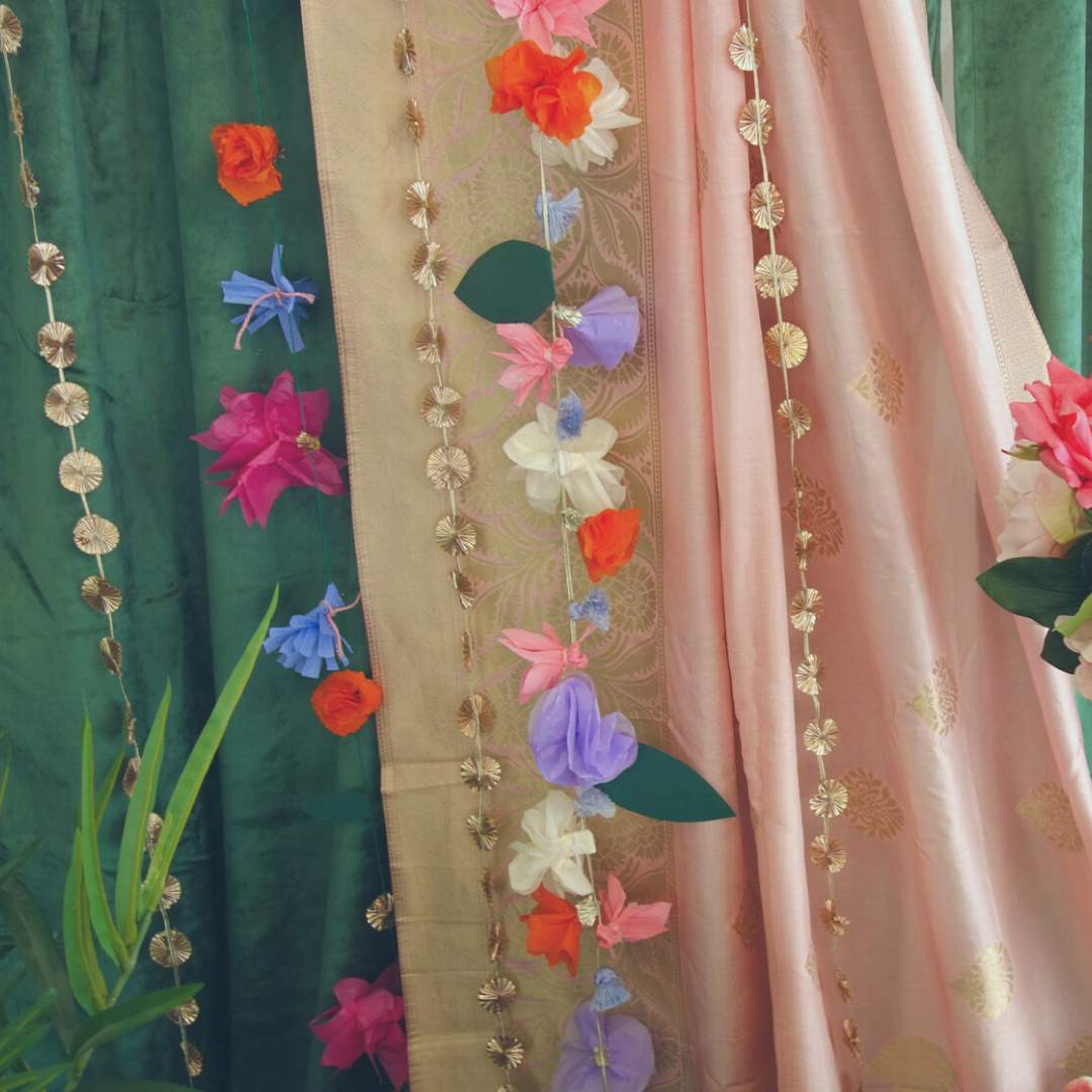 Close up of hanging gota garlands over pink and green backdrop