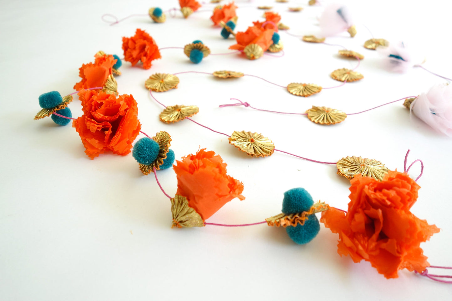 Close up of marigold and teal pom pom party garland set